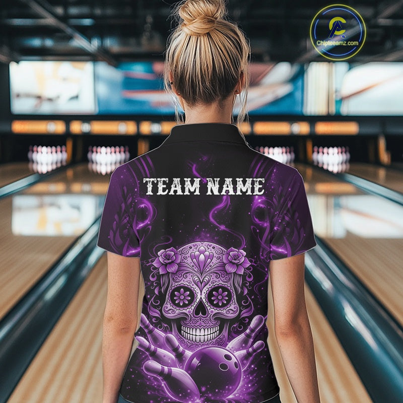 Back view of a female model in a bowling center wearing a black and purple polo featuring a sugar skull above a bowling ball and pins.