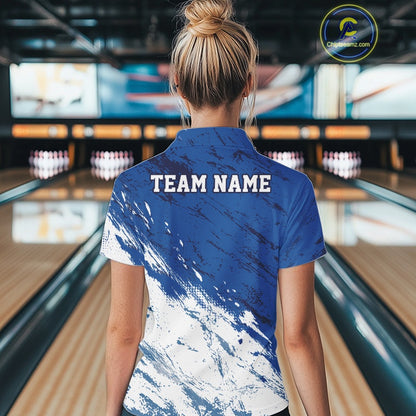 Back view of a female bowler in a bowling alley wearing a white and blue bowling polo shirt with a splatter-inspired sports jersey design