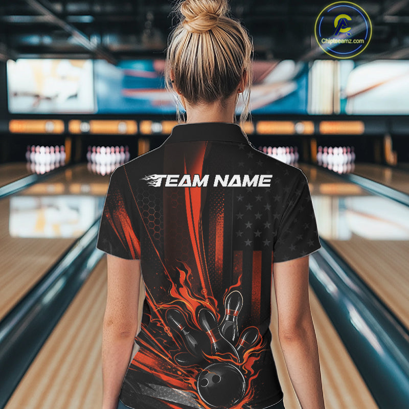 Back view of a female model in a bowling alley wearing a black and orange polo featuring patriotic bowling action artwork with distressed flag styling.