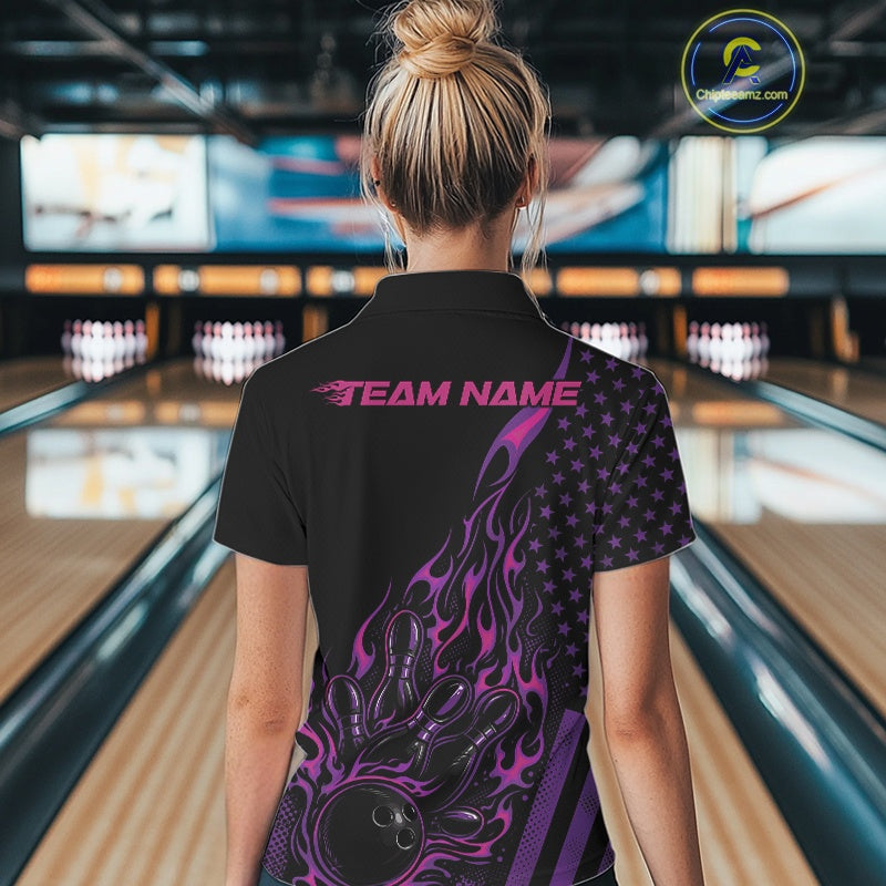Back view of a female model in a bowling venue wearing a black polo shirt featuring a colorful flaming bowling strike scene.