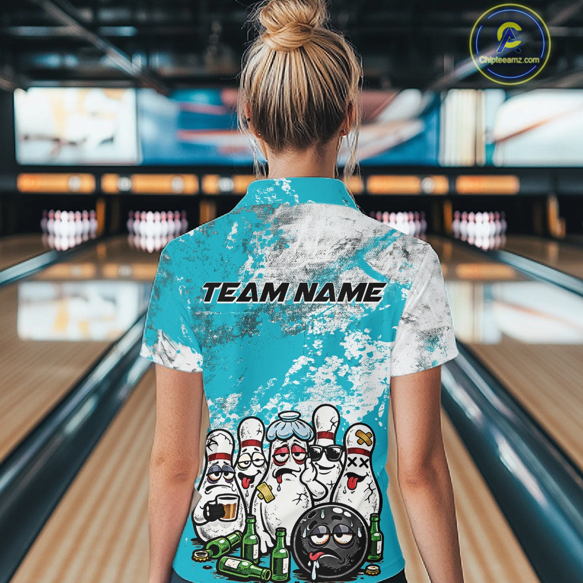 Back view female model in bowling venue wearing white polo shirt with turquoise blue and white splatter pattern, playful bowling pins and bowling ball scene