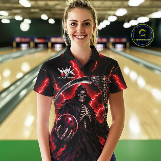 A woman wearing a black short-sleeve polo shirt with a grim reaper graphic, standing in front of a blurred bowling alley background. The shirt features a detailed print of a skeletal figure holding a bowling ball, red lightning, and a scythe, with 'YOUR NAME' and a bowling pin graphic on the chest.