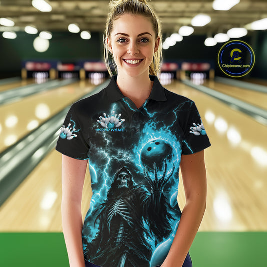 A woman wearing a black short-sleeve polo shirt with a detailed blue and black bowling-themed graphic print, standing in front of a blurred bowling alley background