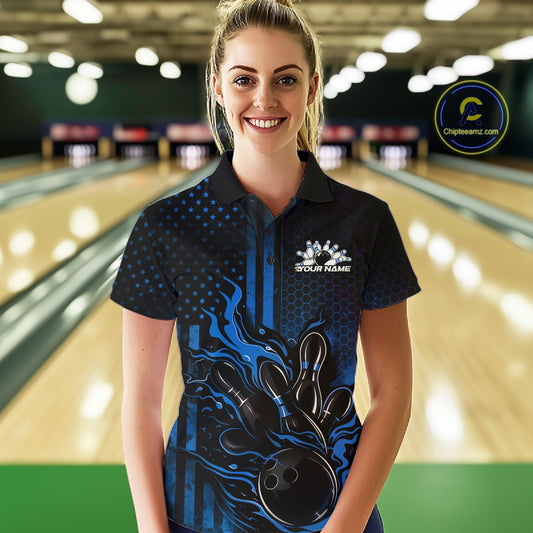 Female model at a bowling lane wearing a black and blue bowling polo shirt with bowling strike graphics, flames, and patriotic elements.