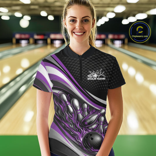 Front view female model wearing black and purple quarter zip bowling shirt in bowling lane, dynamic flame bowling ball and pins design