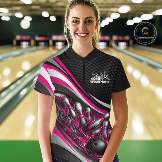 Front view female model wearing black and pink quarter zip bowling shirt in bowling lane, energetic flame bowling ball and pins artwork