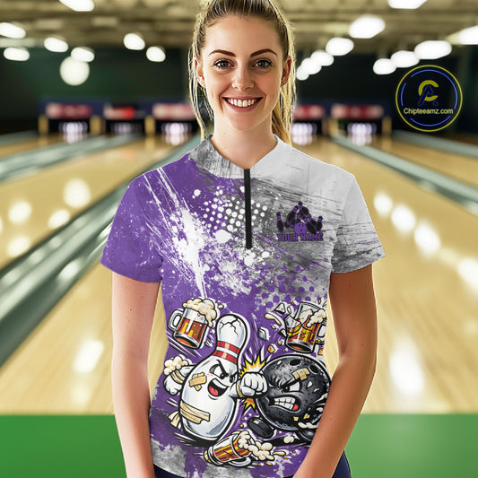 Front view of a female model in a bowling lane wearing a purple and white grunge splatter bowling quarter-zip shirt with humorous cartoon bowling ball and pin battling scene.
