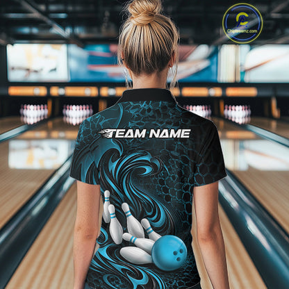 Female model standing in a bowling lane showing the back of a black and blue bowling polo shirt with a tribal flame bowling ball and pins graphic.