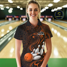 Load image into Gallery viewer, Female model standing in a bowling lane wearing a black and orange bowling polo shirt featuring a tribal flame bowling ball and pins graphic on the front.