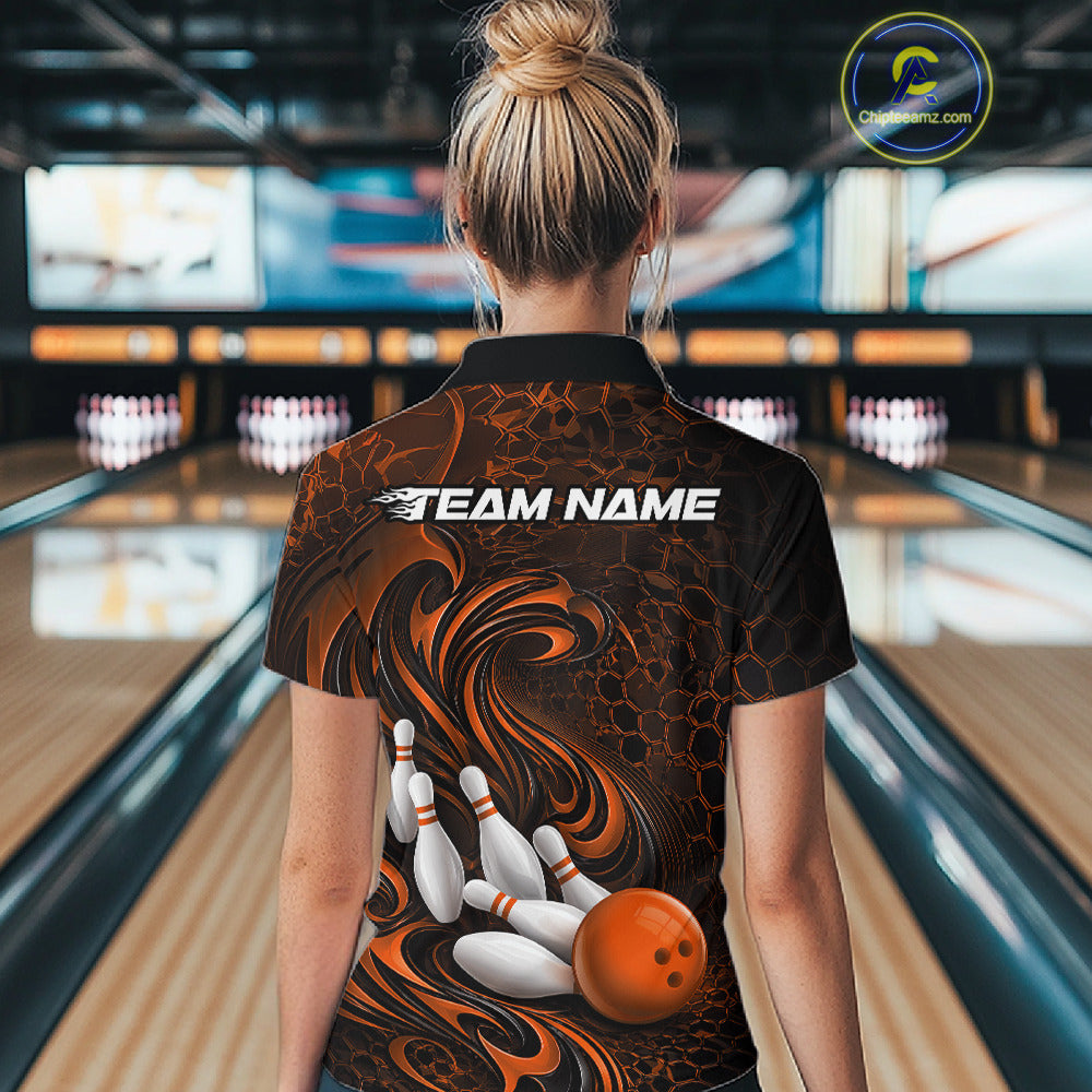 Back view of a female model wearing a black and orange bowling quarter-zip shirt in a bowling alley featuring a tribal flame bowling ball and pins graphic