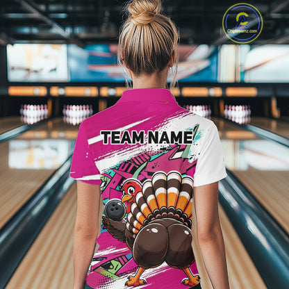 Back view of a female model in a bowling alley wearing a pink custom quarter zip bowling shirt with a funny graffiti turkey holding a bowling ball, paint splatter accents, and a personalized name.