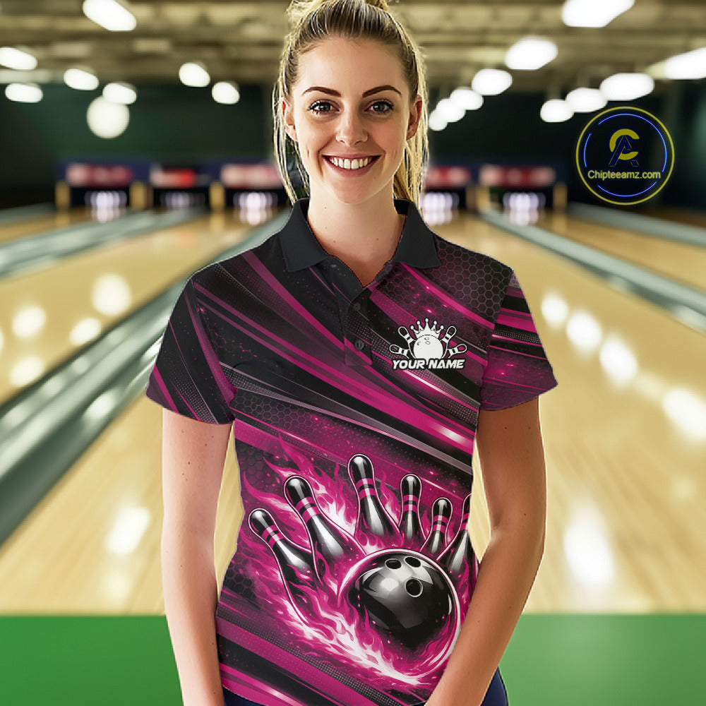 Female model at a bowling lane wearing a black and pink bowling polo shirt with fiery bowling action graphics and dynamic stripe accents.