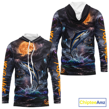 A long-sleeve hooded sweatshirt shown from the front and back, featuring an all-over Halloween-themed graphic print with a jumping blue tuna fish, dark stormy sky, orange full moon, and glowing orange text on the sleeves. The hoodie has a black hood with white drawstrings and a white inner collar.