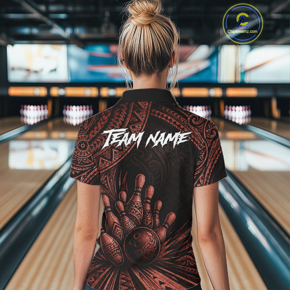 A woman viewed from behind wearing a black short-sleeve bowling shirt with a large brown tribal hand graphic and white 'TEAM NAME' text on the back, standing in a bowling alley.