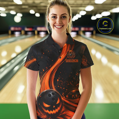 A woman stands in a bowling alley wearing a black short-sleeve polo shirt with a Halloween-themed orange and black graphic print featuring a jack-o'-lantern and bowling ball. The shirt has a customizable chest area with placeholder text.