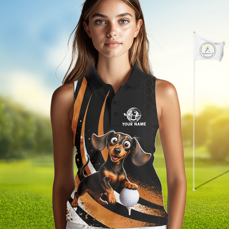 A woman modeling a sleeveless black polo-style top with a colorful printed graphic of a dachshund holding a golf ball, set against a blurred golf course background with a flagpole visible.