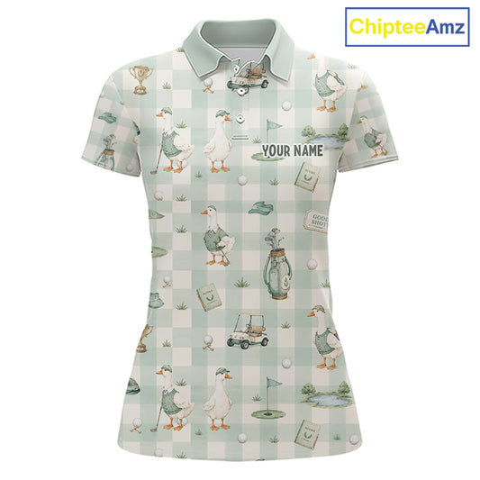 A women's short-sleeve polo shirt with a golf-themed print featuring ducks, golf carts, flags, and a gingham pattern in pale green and white. The shirt has a light green collar and the text 'YOUR NAME' printed on the chest, indicating personalization.