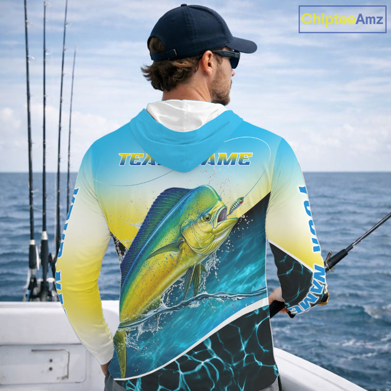 A man on a boat wearing a long-sleeve hooded fishing shirt with a large mahi-mahi fish graphic on the back and 'TEAM name' text across the shoulders. The shirt has a blue-to-yellow gradient with black and white details.