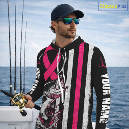A man on a boat wearing a black custom hoodie with pink and white stripes, a fish graphic, and white text reading 'YOUR NAME'. He is also wearing a dark cap and sunglasses, with fishing rods and blue ocean water in the background.