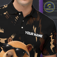 Load image into Gallery viewer, Black polo shirt with gold abstract design and 'Your Name' text, worn by a person, with a capybara wearing sunglasses in the foreground.