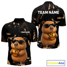 Load image into Gallery viewer, Two black shirts with a capybara holding a gold ball design, one with 'Your Name' and 'Team Name' text, the other with 'Chiptee Amz' branding.