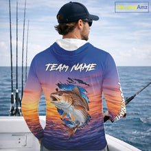 Load image into Gallery viewer, Angler wearing Redfish Fishing Sunset custom long sleeve hooded redfish offshore fishing shirt on the boat at sunset