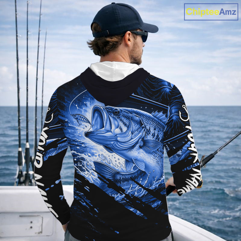 Person wearing a blue and black bass fishing shirt with a fish design, standing by the ocean.